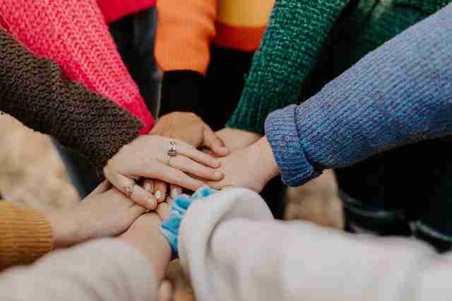 Team members joining hands in a collaborative gesture.
